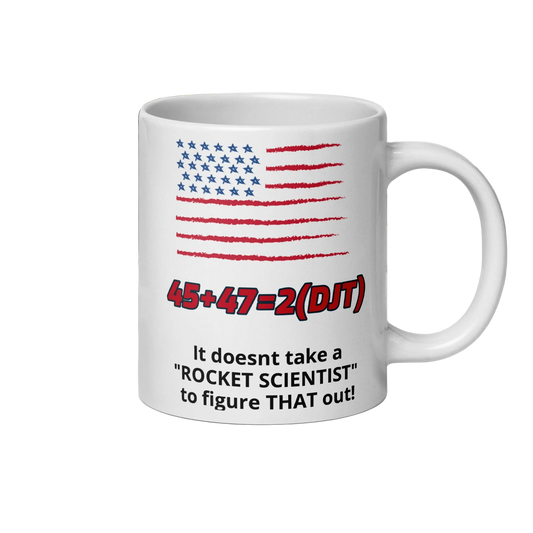 A white ceramic coffee mug featuring a hand-drawn American flag in red and blue, the equation '45+47=2(DJT)' in red, and the text 'It doesnt take a "ROCKET SCIENTIST" to figure THAT out!' in black.
